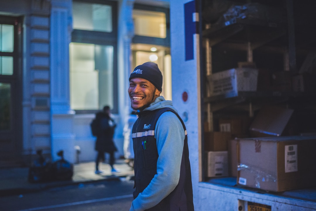 smiling-man-stands-behind-delivery-truck-t0aio60jd4q